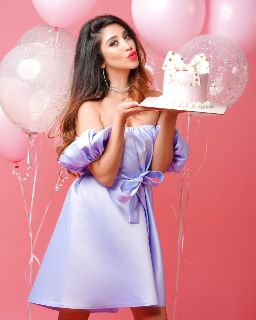 woman in pink dress holding white and pink happy birthday cake